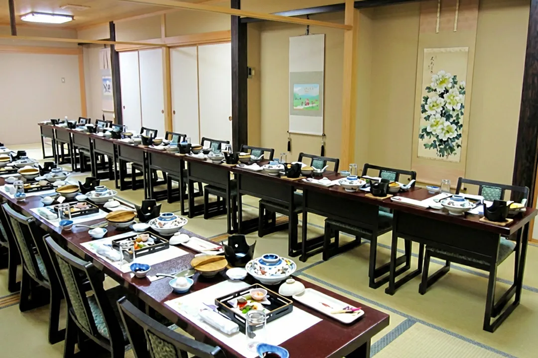 畳の広間に座卓と椅子が多数並べられ、大人数の団体での食事が可能な和風の宴会場。