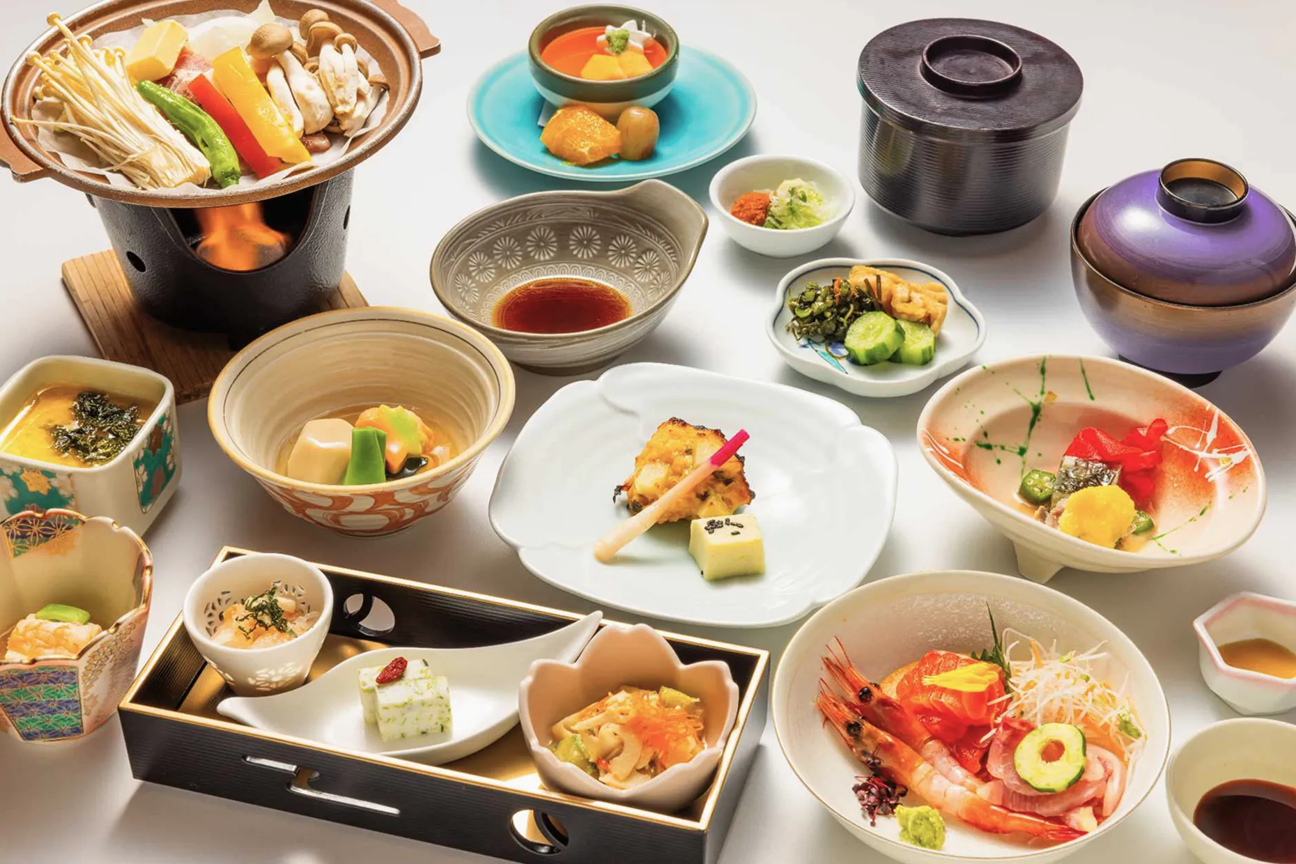 土鍋の煮物や刺身、八寸など、様々な器に美しく盛り付けられた豪華な旬の懐石料理。