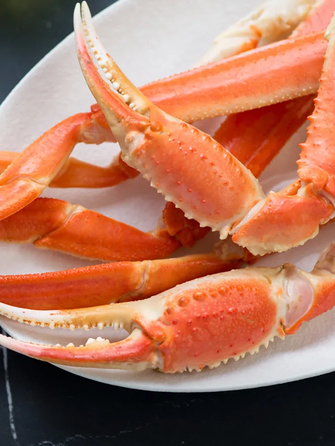 茹でて赤く色づいた、皿に盛られた数本のカニの脚