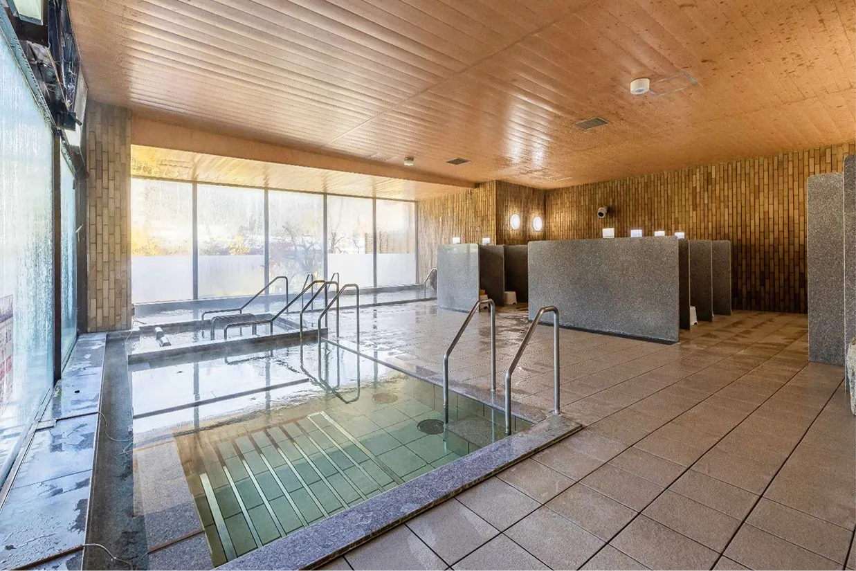 大きな窓から光が差し込む、広々とした清潔感のある大浴場の内湯。