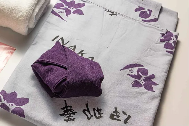 紫色の花柄があしらわれた落ち着いたグレーの浴衣と、きれいに折り畳まれた濃い紫色の帯。横には清潔な白いタオルが添えられている