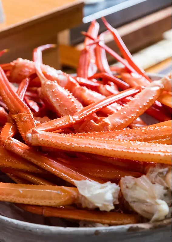 茹でられたカニの鮮やかな赤い脚が皿に山盛りにされたクローズアップ。