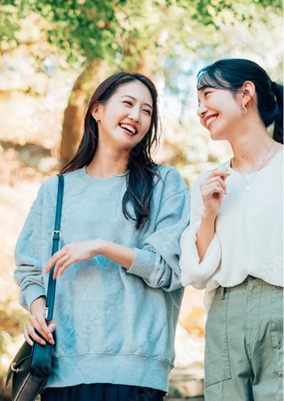 屋外で明るく笑い合う女性2人。