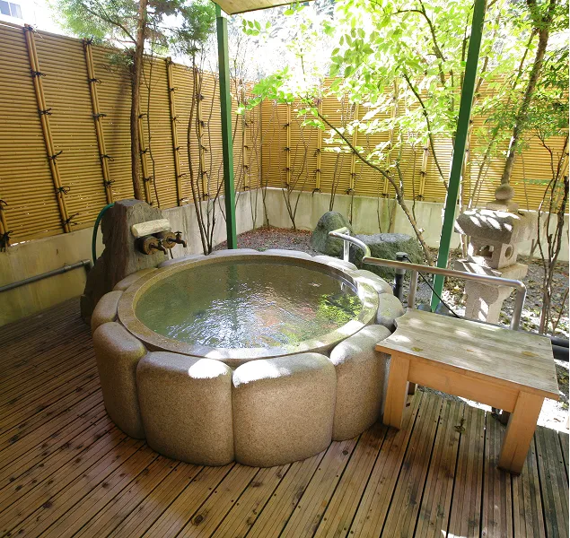 木のデッキの上に設置された、丸い石造りの壺風呂のような露天風呂。