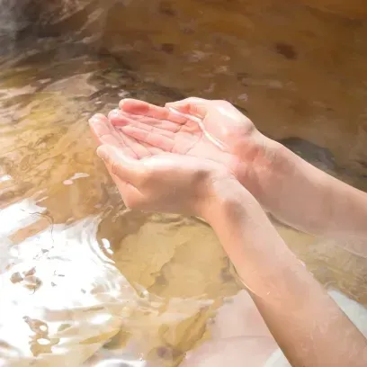 温かい温泉の湯を両手でそっとすくう様子。