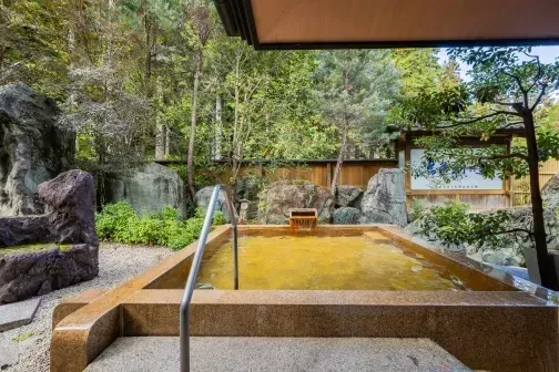 深い緑と岩に囲まれた、黄色い湯の天然露天風呂。