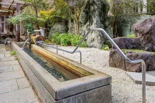 庭園に設置された、石造りの長い水路と木の湯口。
