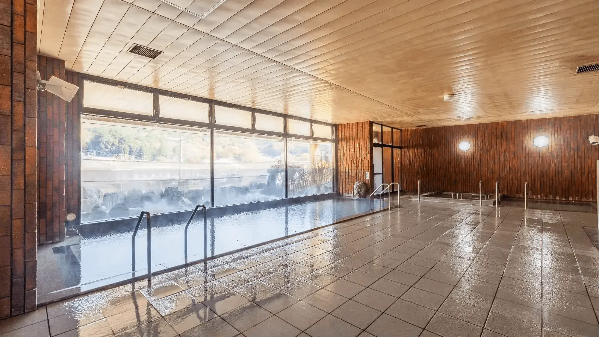 窓際の広い大浴場と温泉プール