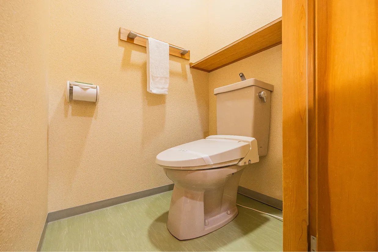 ゆとりのあるトイレ。壁面には手拭きタオルとペーパーホルダーが配置され、清潔に保たれています。