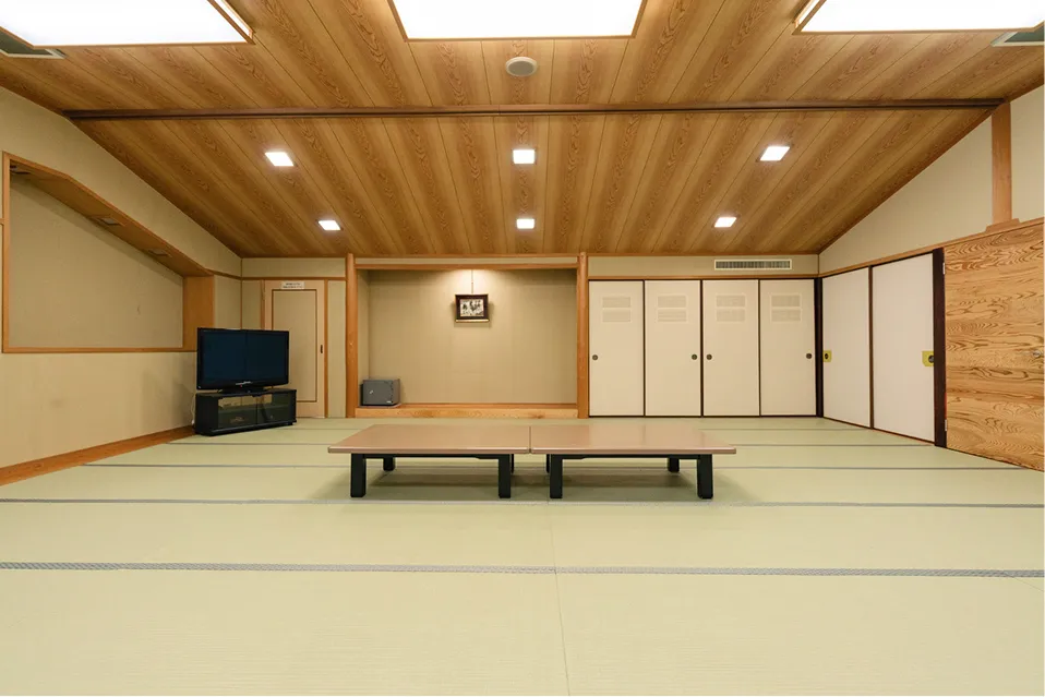 高い天井が印象的な広々とした和室。正面には床の間があり、大人数が一堂に会せる大きな座卓と、カラオケを楽しめる大型テレビが備わっています。