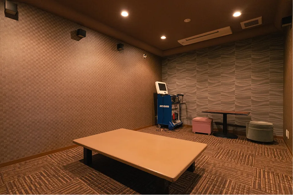 お部屋に併設された専用カラオケルーム。落ち着いた照明の室内には、カラオケ機材と大型モニター、ゆったりと座れるテーブルとスツールが備わり、周囲を気にせずプライベートな歌唱タイムを楽しめます。