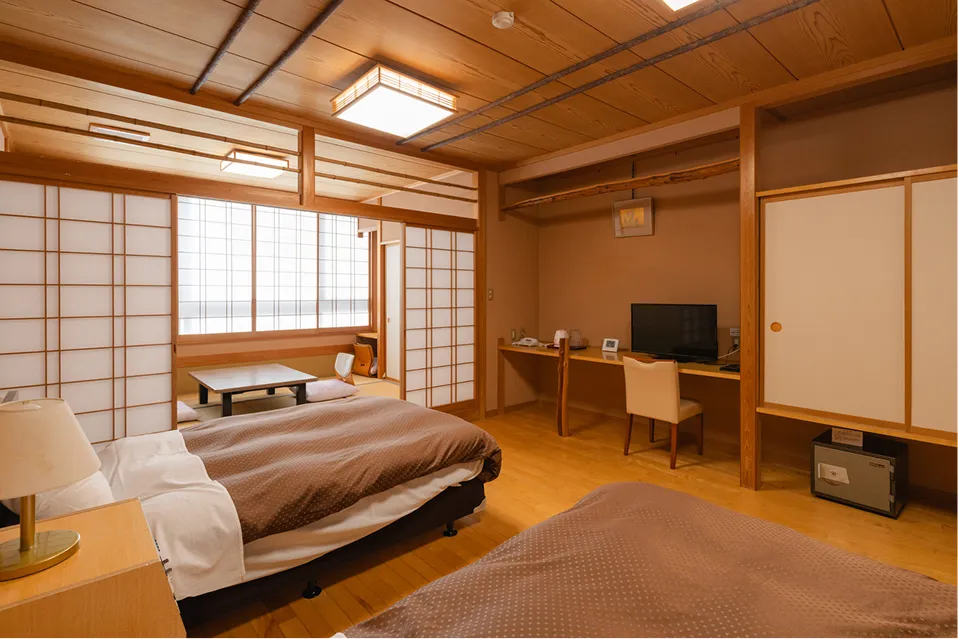 手前にゆったりとしたツインベッド、奥に一段高い畳の間を配した和洋室。障子から差し込む光が室内を柔らかく包み込み、和と洋が調和した広々とした空間です。